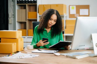 Başlangıçta küçük işletme KOBİ 'si, akıllı telefon ve bilgisayar kullanan girişimci kadın paket ürün kutularını hazırlamak için çevrimiçi satın alma siparişi alır ve kontrol eder