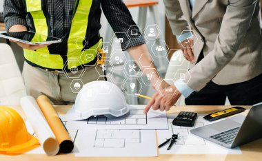 Müteahhit ve mimar planı tablet, dizüstü bilgisayar kullanarak ve büyük bir proje üzerinde çalışmakla ilgili konuşarak ele alıyorlar. İnşaat sürecinde bina içi