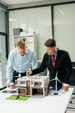 Bir iş toplantısının mimarları, modern bir yapı modelini planlamak ve tartışmak, mimari tasarımda takım çalışması ve yaratıcılığı sergilemek