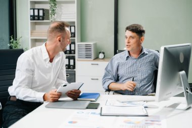 İki iş adamı ofiste iş projelerini tartışıyor.