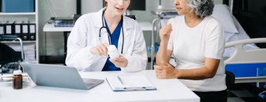 Portrait of female doctor with her patient. Doctor giving advices to patient in hospital room. clipart