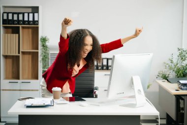 Bilgisayarda çalışan ve yaratıcı ofiste el kol hareketi yapan kendine güvenen bir iş kadını.