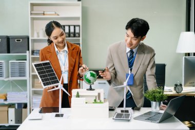 İş adamlarının şirket ofisinde rüzgar enerjisi hakkında görüşleri var. İş ekibi yel değirmeni ve alternatif yeşil enerji hakkında konuşuyor. Ağ sıfır ve karbon nötr konsept.