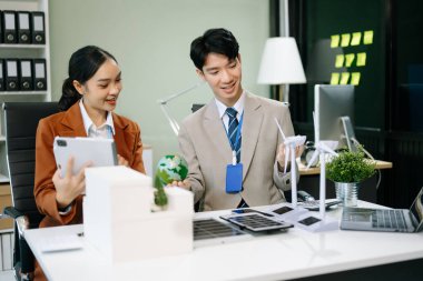 İş adamlarının şirket ofisinde rüzgar enerjisi hakkında görüşleri var. İş ekibi yel değirmeni ve alternatif yeşil enerji hakkında konuşuyor. Ağ sıfır ve karbon nötr konsept.