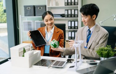 İş adamlarının şirket ofisinde rüzgar enerjisi hakkında görüşleri var. İş ekibi yel değirmeni ve alternatif yeşil enerji hakkında konuşuyor. Ağ sıfır ve karbon nötr konsept.