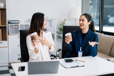 Genç iş adamları yeni bir proje üzerinde çalışıyor. Toplantının proje yöneticileri dizüstü bilgisayar kullanıyor ve kahve içiyor.