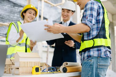 Mimar Asyalı takım inşaat alanında iş arkadaşlarıyla birlikte çalışıyor. Büyük projede mimarlık mühendisliği. İnşaat sürecinde bina içi.