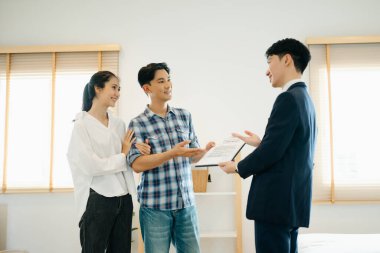 Asyalı emlak komisyoncusu, dosyasında ev detaylarını görmek isteyen Asyalı genç çifte gösteriyor. Yeni bir ev konsepti satın almak