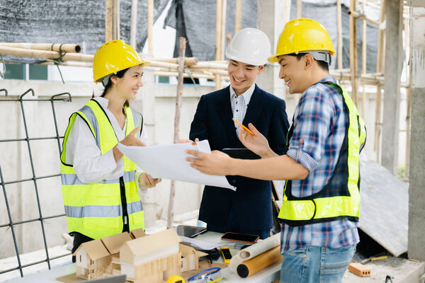Архитектор азиатской команды работает с коллегами на строительной площадке. Архитектурное проектирование на большом проекте. Строительство интерьера в процессе строительства.