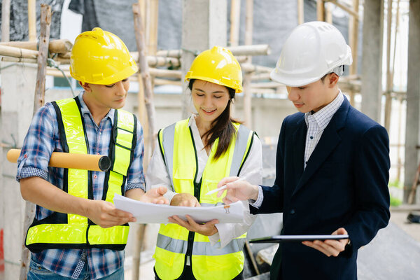 Архитектор азиатской команды работает с коллегами на строительной площадке. Архитектурное проектирование на большом проекте. Строительство интерьера в процессе строительства.