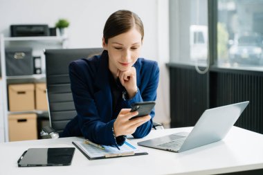 Yaratıcı ofiste akıllı telefon kullanan kendine güvenen bir iş kadını. 