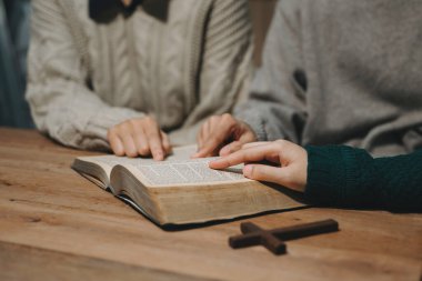 Bir grup Hıristiyan birlikte oturup odalarında İncil 'le ahşap bir masanın etrafında dua ediyorlar. Allah 'ın lütuf ve ihsanını dileyin..