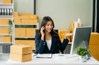 Genç işletme sahibi akıllı telefondan konuşan müşterilere çevrimiçi siparişleri kontrol ediyor. Çevrimiçi Alışveriş kavramı.