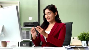 Kendine güvenen iş kadını yaratıcı ofiste bilgisayarla çalışıyor ve akıllı telefon kullanıyor.