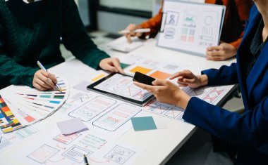  UX geliştiricileri ve ui tasarımcıları modern ofiste müşteri özeti ve renk kodu ile mobil uygulama arayüzü kablo tasarımı hakkında beyin fırtınası yapıyorlar