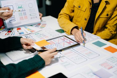  UX geliştiricileri ve ui tasarımcıları modern ofiste müşteri özeti ve renk kodu ile mobil uygulama arayüzü kablo tasarımı hakkında beyin fırtınası yapıyorlar