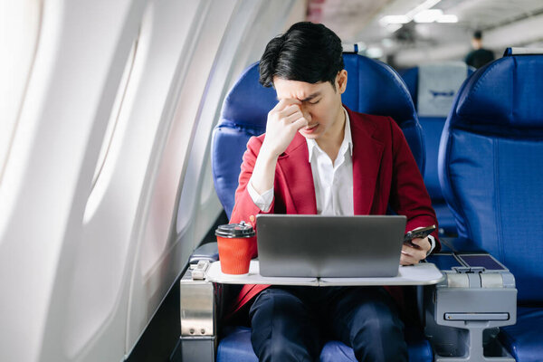 Портрет успешного азиатского бизнесмена в официальном костюме на самолете, сидящем в бизнес-классе.
