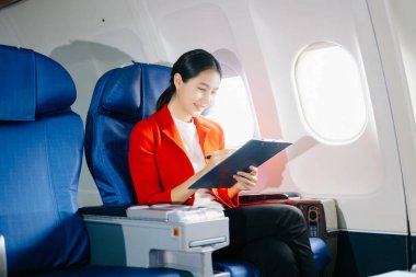 Uçakta bir koltukta oturan Asyalı kadın, pano ve seyahat konseptiyle.