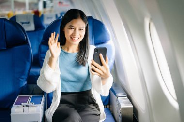 Asyalı kadının uçuş sırasında akıllı telefondan bir görüntülü arama var.  