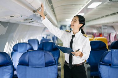 Asyalı kendinden emin, üniformalı kadın pilot uçağın içinde duruyor.