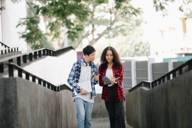 İki öğrenci kampüs parkını inceliyor. Gençler birlikte vakit geçiriyorlar. Kitap ve dizüstü bilgisayarı merdivenlerde tutmak 