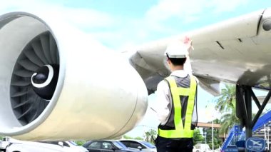 Bir uçak motorunu denetleyen, profesyonellik ve endüstri standartlarını somutlaştıran güvenlik donanımı mühendisi..