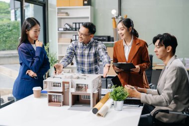 Laptop ve tablet kullanarak yenilikçi binalar tasarlayan Asyalı profesyonellerle modern bir mimari ofis toplantısını keşfedin. 