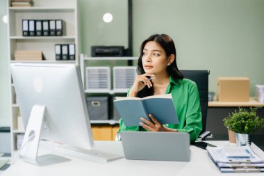 Genç Asyalı iş kadını modern ofiste bilgisayar üzerinde çalışıyor.