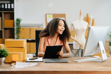 Başlangıçta küçük işletme KOBİ 'si, İş kadını bilgisayar kullanarak ve pano tutarak online alışveriş siparişi alır ve kontrol eder 