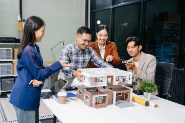 Tablet kullanarak yenilikçi binalar tasarlayan Asyalı profesyonellerle modern bir mimari ofis toplantısı keşfedin. 