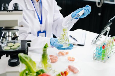 Laboratuvarda ileri teknoloji ve hassas ekipman kullanılarak güvenlik ve kalite için mikro yeşil yaprakları test ve analiz eden kadın laboratuvar bilimcisi.