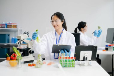 Laboratuvarda ileri teknoloji ve hassas ekipmanlar kullanarak sebzeleri güvenlik ve kalite için test edip analiz eden kadın laboratuvar bilim adamları.