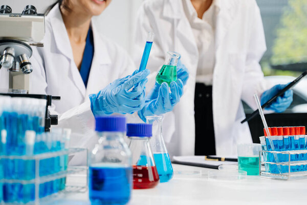 Young scientists conducting research investigations in a medical laboratory using a microscope and digital tablet