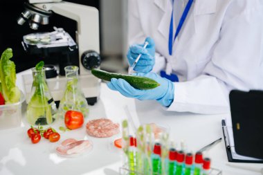 Laboratuvarda ileri teknoloji ve hassas ekipmanlar kullanarak salatalığı güvenlik ve kalite için test ve analiz eden kadın laboratuvar bilim adamı.