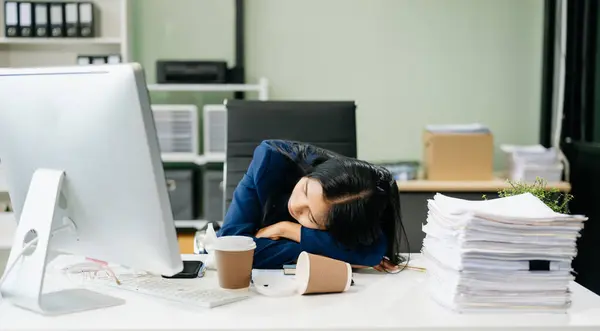 stock image Asian businesswoman is stressed, bored, and overthinking from working on a computer and documents at the modern office