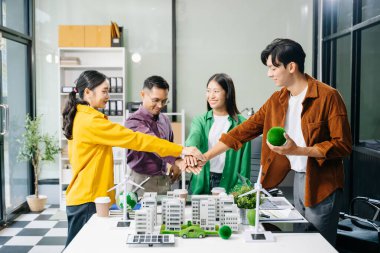 Masanın yanında duran çeşitli iş adamlarından oluşan bir grup konut projesi ve istifleme el modeline bakıyor. Yeşil iş şirketi ve Güneş Enerjisi Çevre Kenti Kavramı