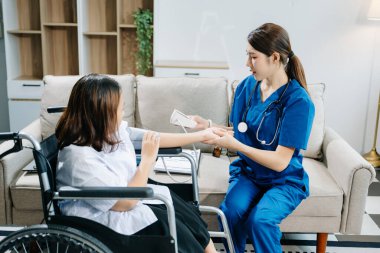 Asyalı genç bayan hemşire tekerlekli sandalyedeki kadın hastanın kan basıncını ölçüyor. Tıbbi bir ortamda özen, şefkat ve profesyonellik gösterme.