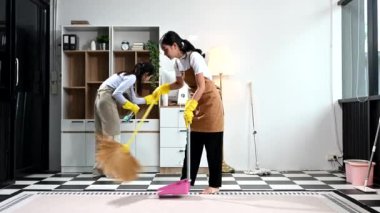 İki Asyalı kadın temizlikçi verimli ve profesyonel temizlik yapıyor. Mükemmel takım çalışması her evde lekesiz temizlik sağlar.. 