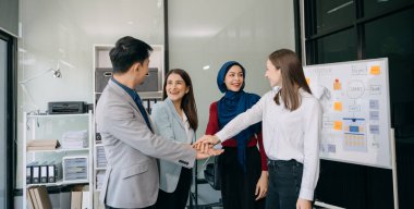Takım çalışması konsepti, bir grup iş arkadaşının ofiste yaptıkları toplantıda el ele tutuşması.