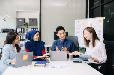 Ofiste yeni bir proje üzerinde çalışırken mutlu iş adamları. Ofiste bir dizüstü bilgisayar ve tablet kullanan bir grup iş adamı