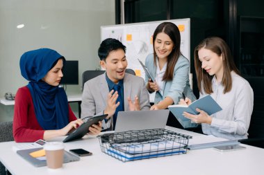 Ofiste yeni bir proje üzerinde çalışırken mutlu iş adamları. Ofiste bir dizüstü bilgisayar ve tablet kullanan bir grup iş adamı