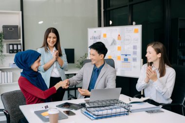 Ofiste yeni bir proje üzerinde çalışırken mutlu iş adamları. Ofiste bir dizüstü bilgisayar ve tablet kullanan bir grup iş adamı
