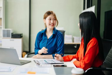 Modern ofiste dizüstü bilgisayarda çalışan Asyalı iş arkadaşları. Takım çalışması, finansal pazarlama ekibi.