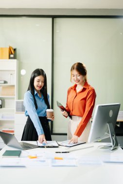 Asyalı iş adamlarının modern ofiste dizüstü bilgisayar, tablet ve bilgisayar kullanarak birlikte çalıştıkları başarı portresi. takım çalışması konsepti 