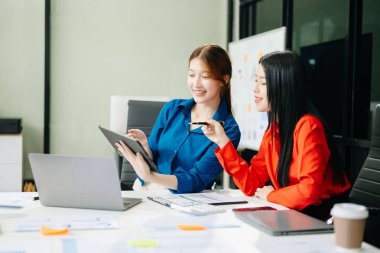 Modern ofiste dizüstü bilgisayarda çalışan Asyalı iş arkadaşları. Takım çalışması, finansal pazarlama ekibi.