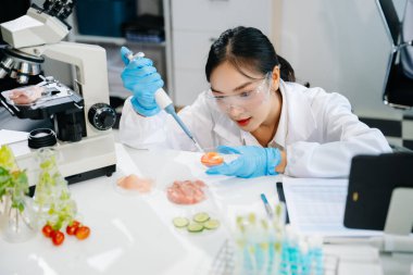 Laboratuvar önlüklü kadın gıda bilimcisi, numuneleri test ediyor ve modern bir laboratuvar ortamında gıda güvenliği ve kalitesini analiz ediyor.