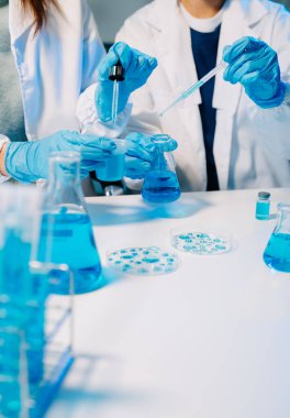 Laboratuvar önlüklü bilim adamları modern bir yüksek teknoloji laboratuvarında kimyasallarla çalışıyorlar..