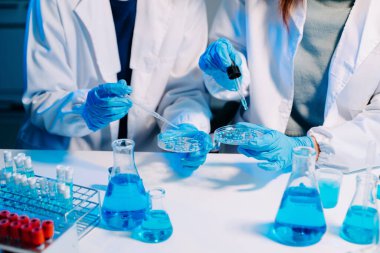 Laboratuvar önlüklü bilim adamları modern bir yüksek teknoloji laboratuvarında kimyasallarla çalışıyorlar..