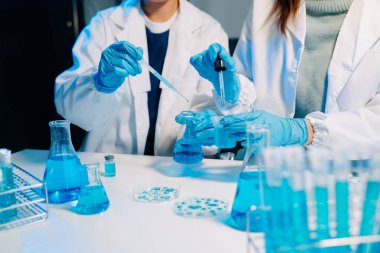 Laboratuvar önlüklü bilim adamları modern bir yüksek teknoloji laboratuvarında kimyasallarla çalışıyorlar..