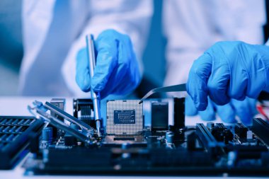 Teknisyenlerin orta bölümü işlemciyi ana bilgisayarın prizine yerleştiriyor. Elektronik mühendislik, elektronik tamir, elektronik ölçüm ve testler, tamir konsepti. 